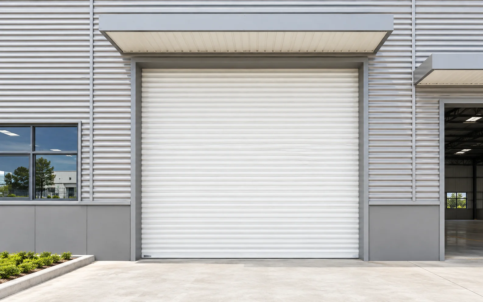 White steel roller shutter door with an enclosed headbox at an exterior factory entrance